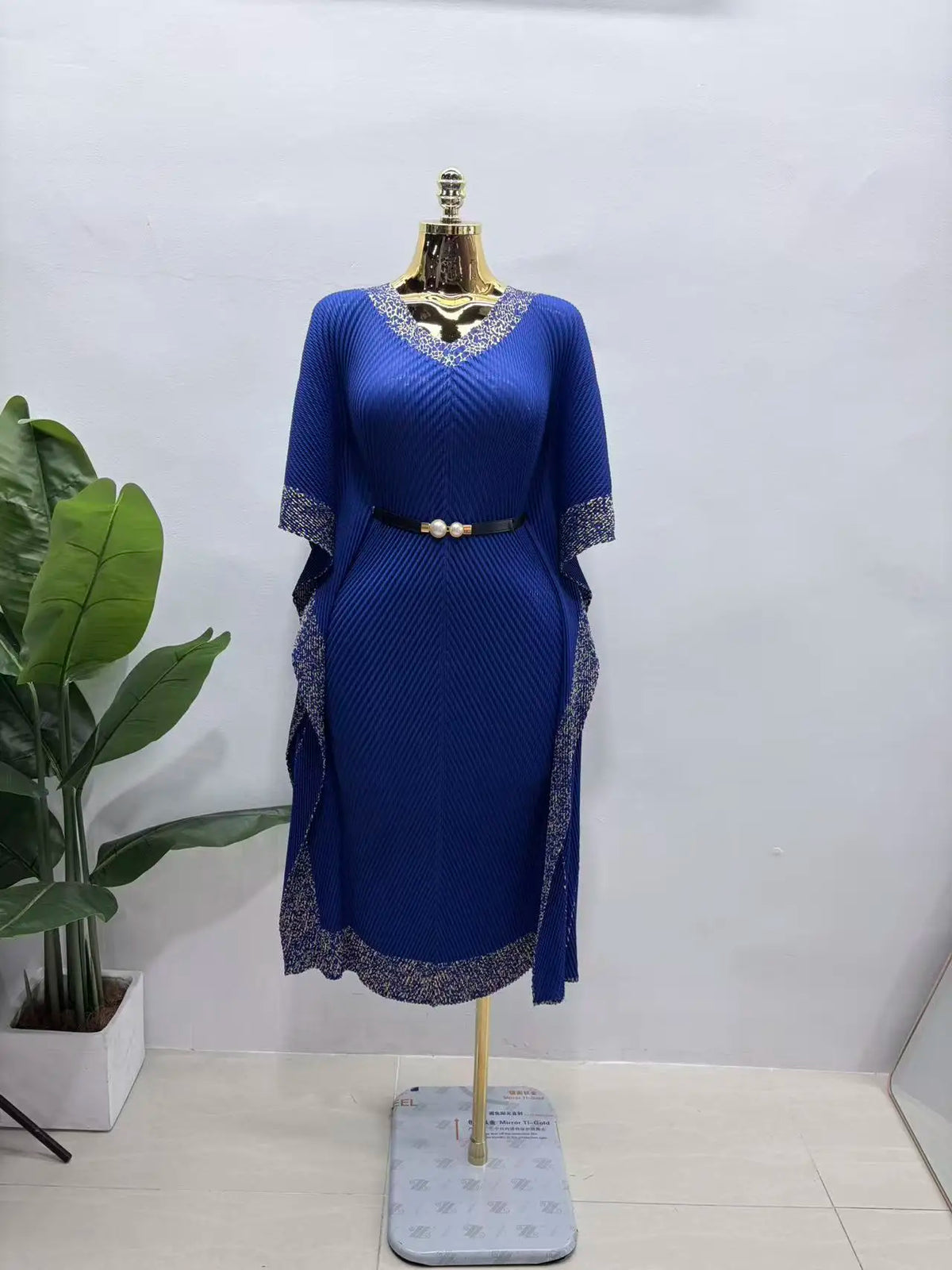 Africa-inspired V-neck long dress by JN Fashion Fusion featuring bat sleeves, dragon scale pleats, fringe, and bronzing details.